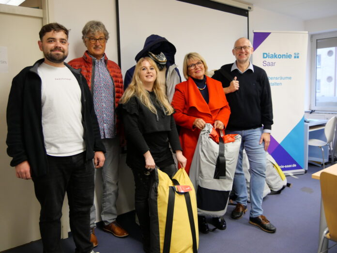 Michael Meyer (2.v.l.) und Ingrid Meyer (2.v.r.) übergaben heute die Sheltersuits - eine Kombination aus Jacke und Schlafsack - an die Wohnungslosenhilfe der Diakonie Saar (links und Mitte: Sozialarbeitende Tobias Braun und Julia Schweitzer, rechts Geschäftsführer Matthias Ewelt) - Foto: Diakonie Saar / Stein